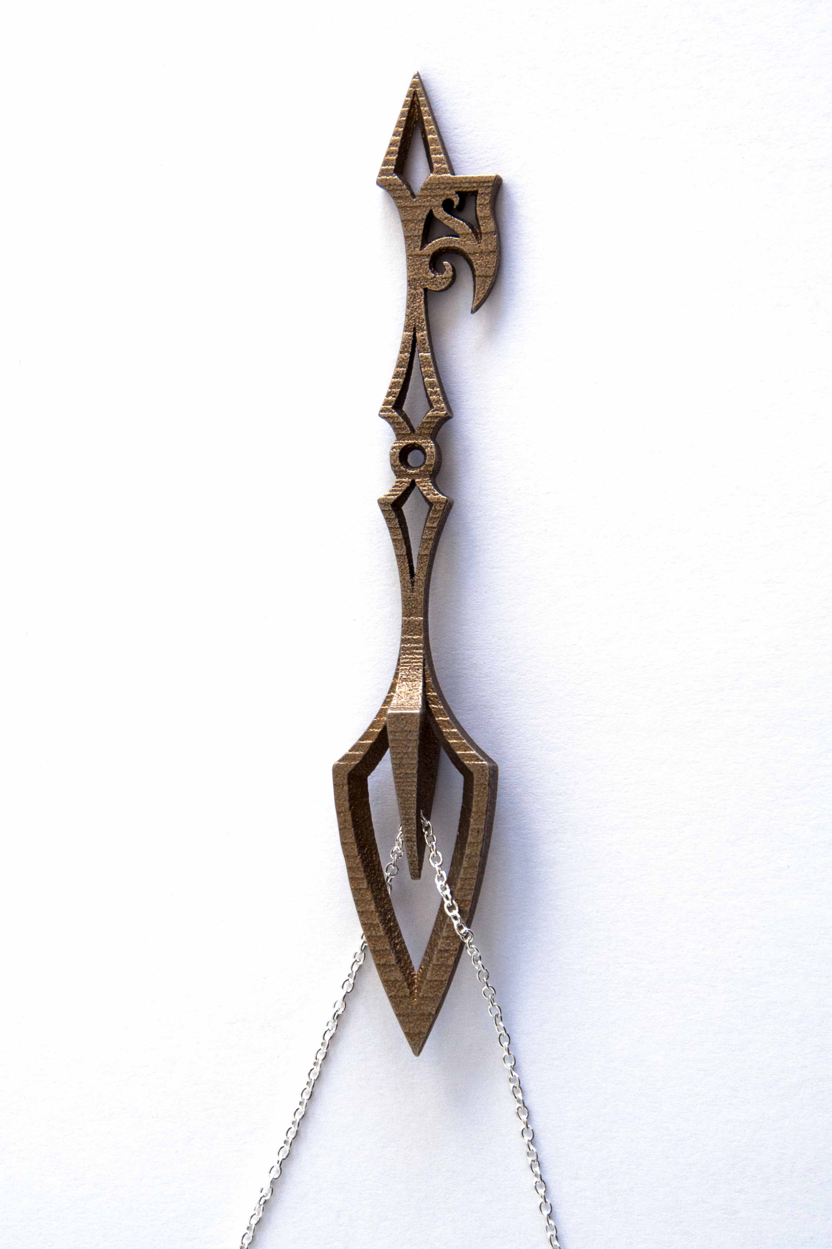 A bronze-colored skeleton key defined by pointed ends, curved edges, and negative space.